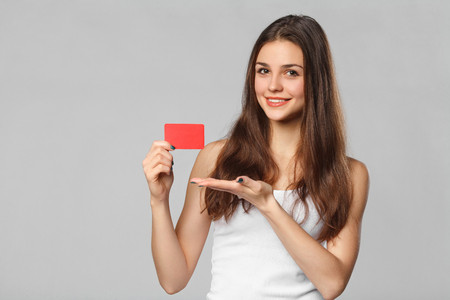 59692234 mujer sonriente que muestra la tarjeta de crédito en blanco en la camiseta blanca aislado sobre fond